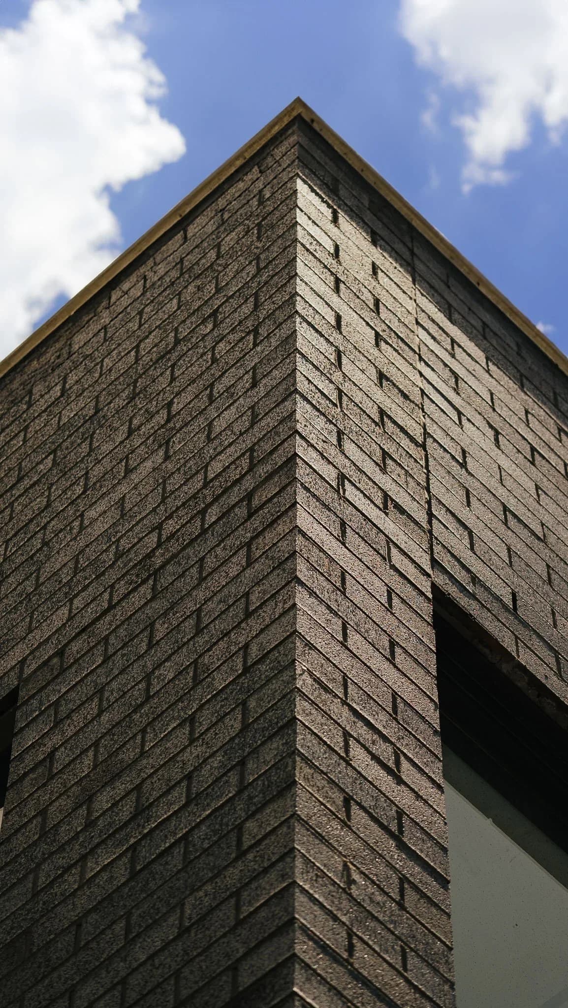 The brick corner of the new clubhouse against a blue sky