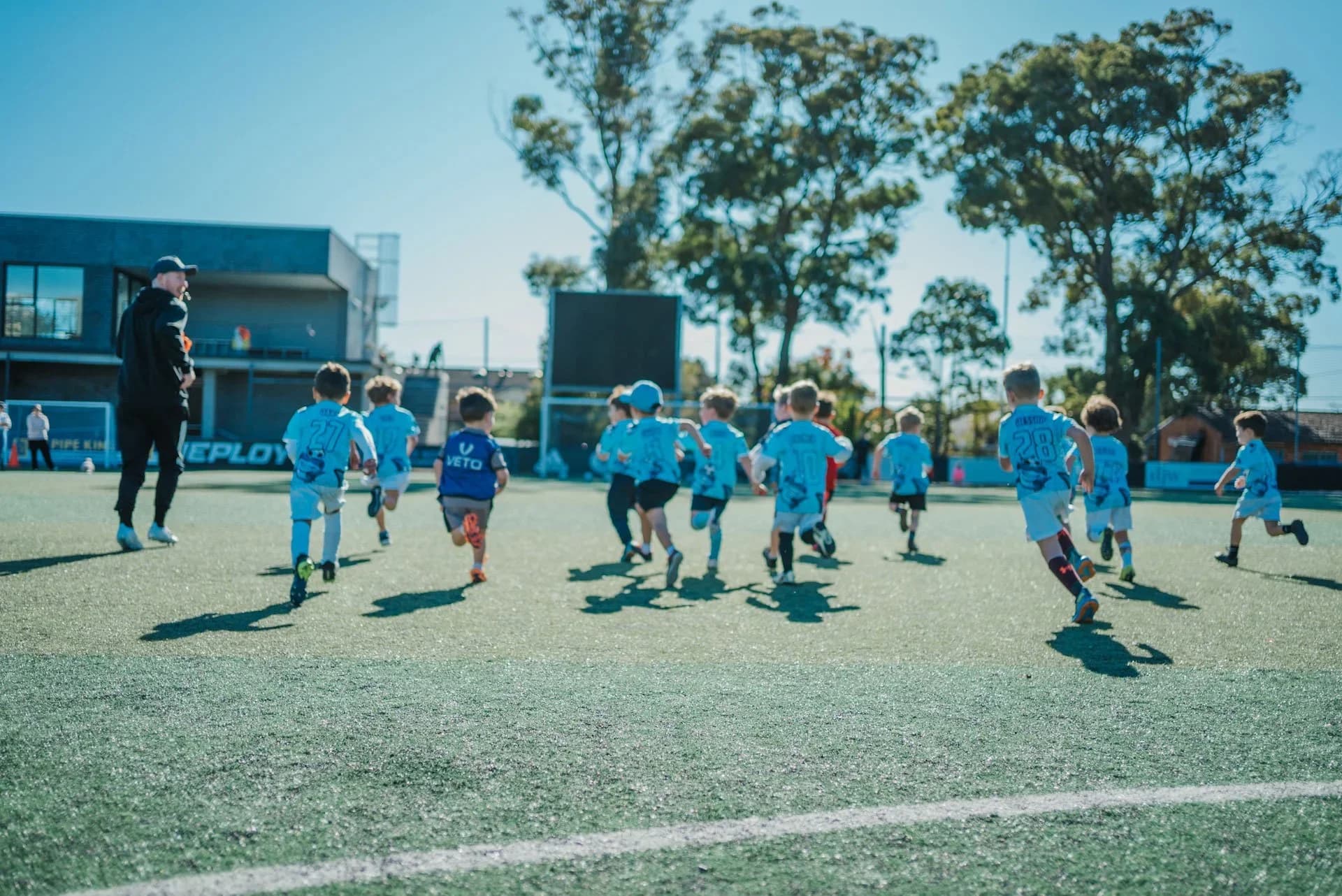 Children in sky-blue tops run across the pitch at a holiday camp