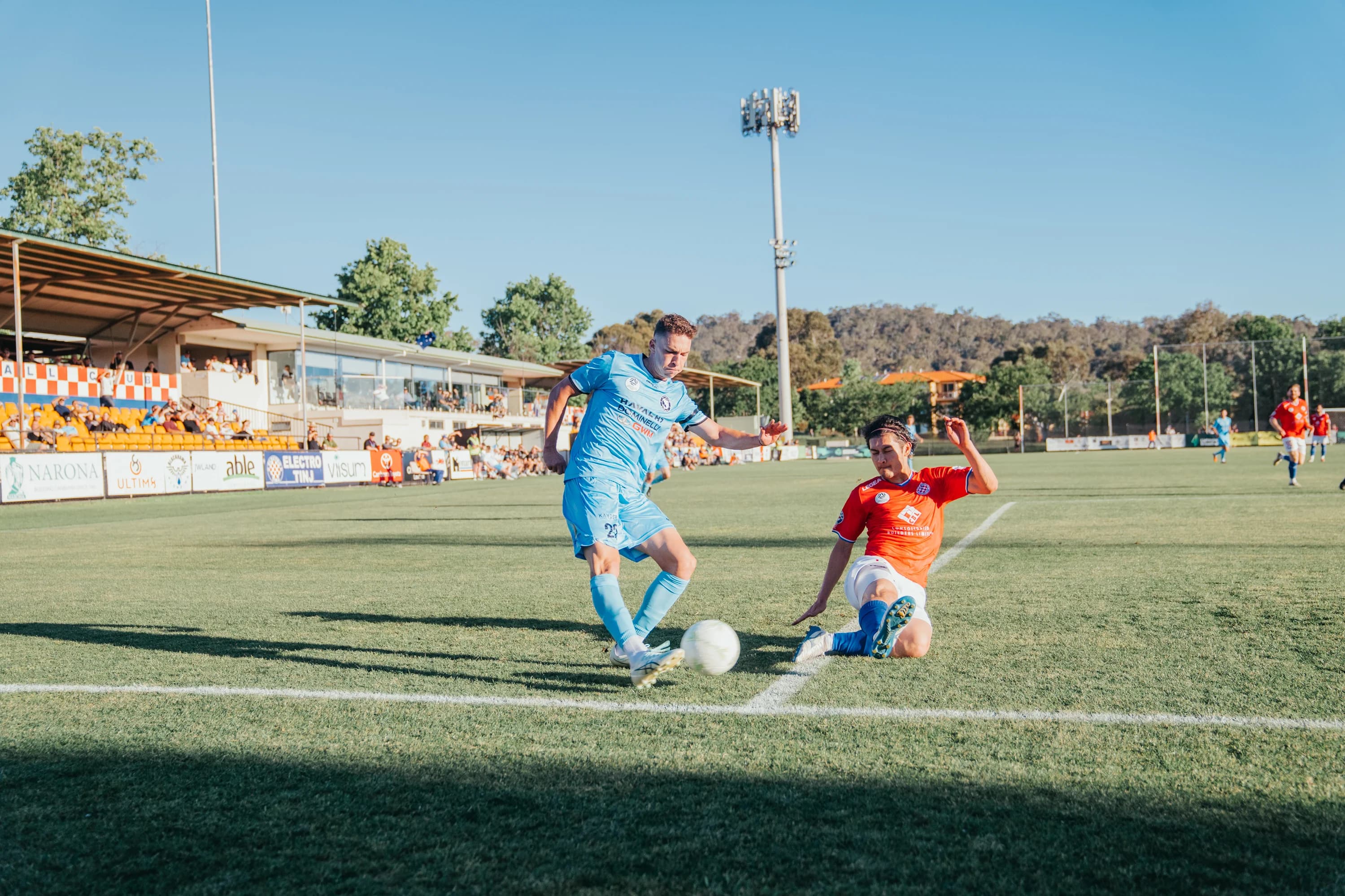 A Sharks attacker in sky blue takes the ball past Canberra Croatia's goalkeeper as he slides in at Deakin Stadium