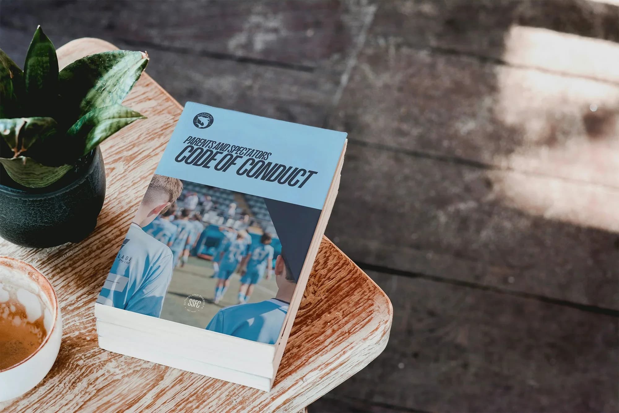 A copy of the club's Code of Conduct booklet on a wooden table