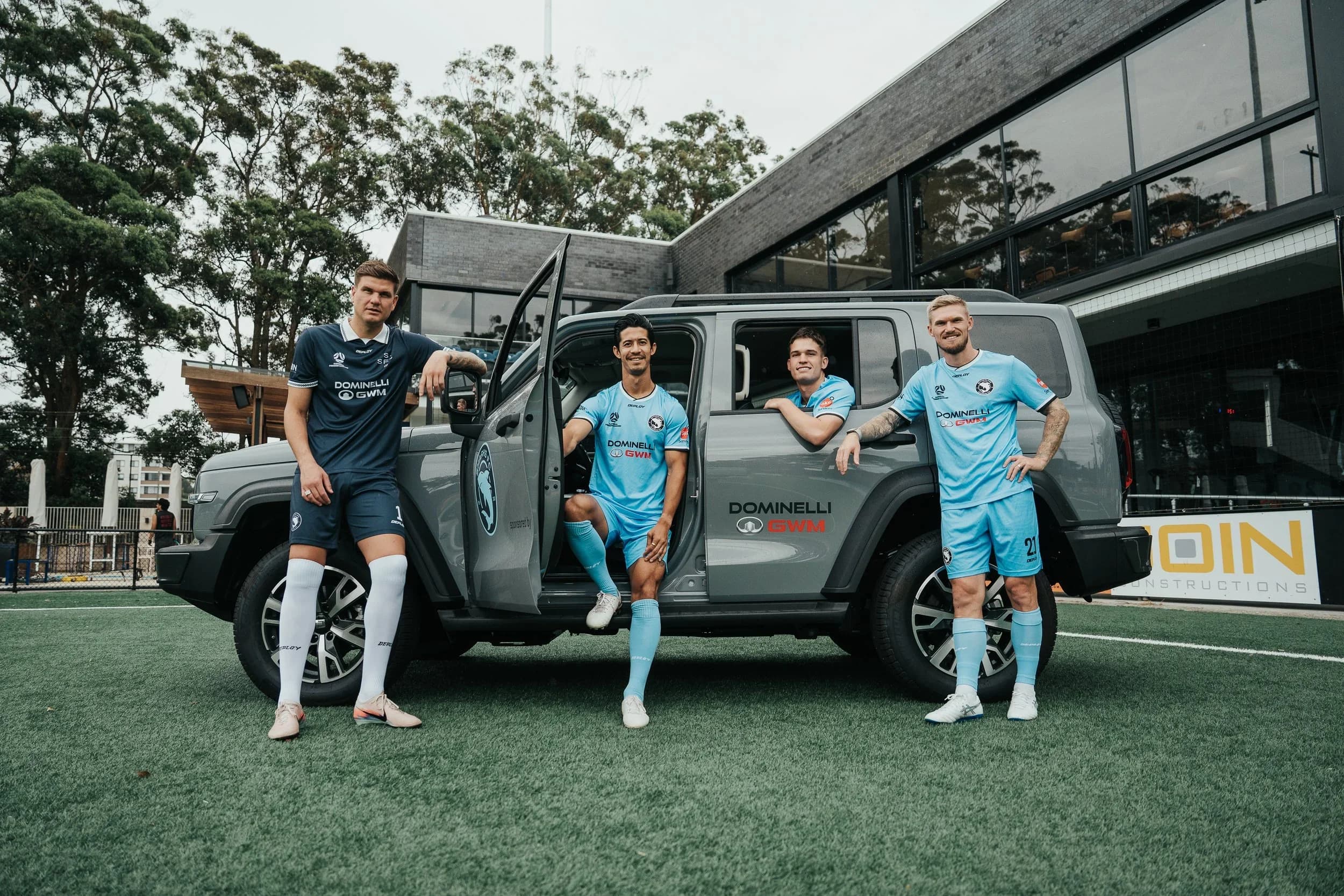 Sharks players with a grey Dominelli GWM car on the pitch at Seymour Shaw