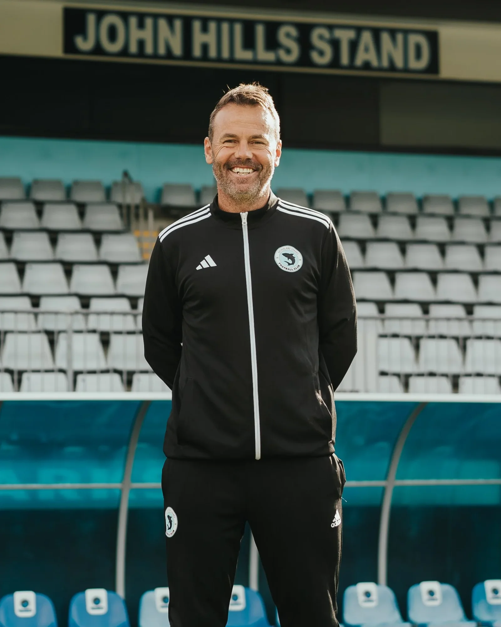 Paul Reid in a black club jacket in front of the John Hills Stand