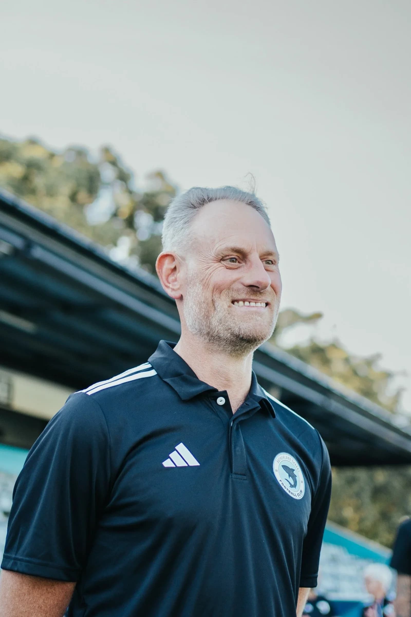 James Webb smiling in a navy club polo at Seymour Shaw