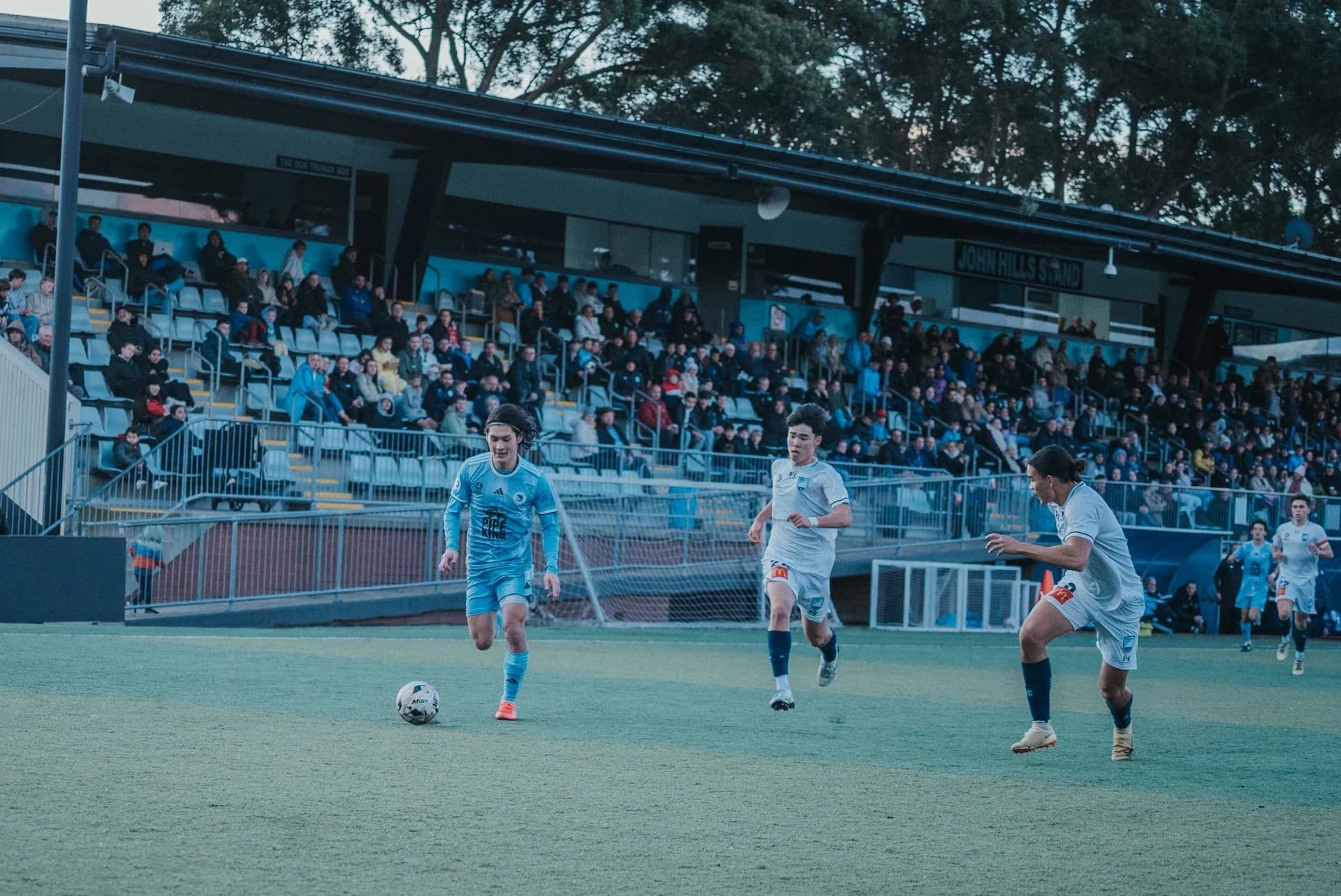 Sharks players in sky blue in action in front of a full stand