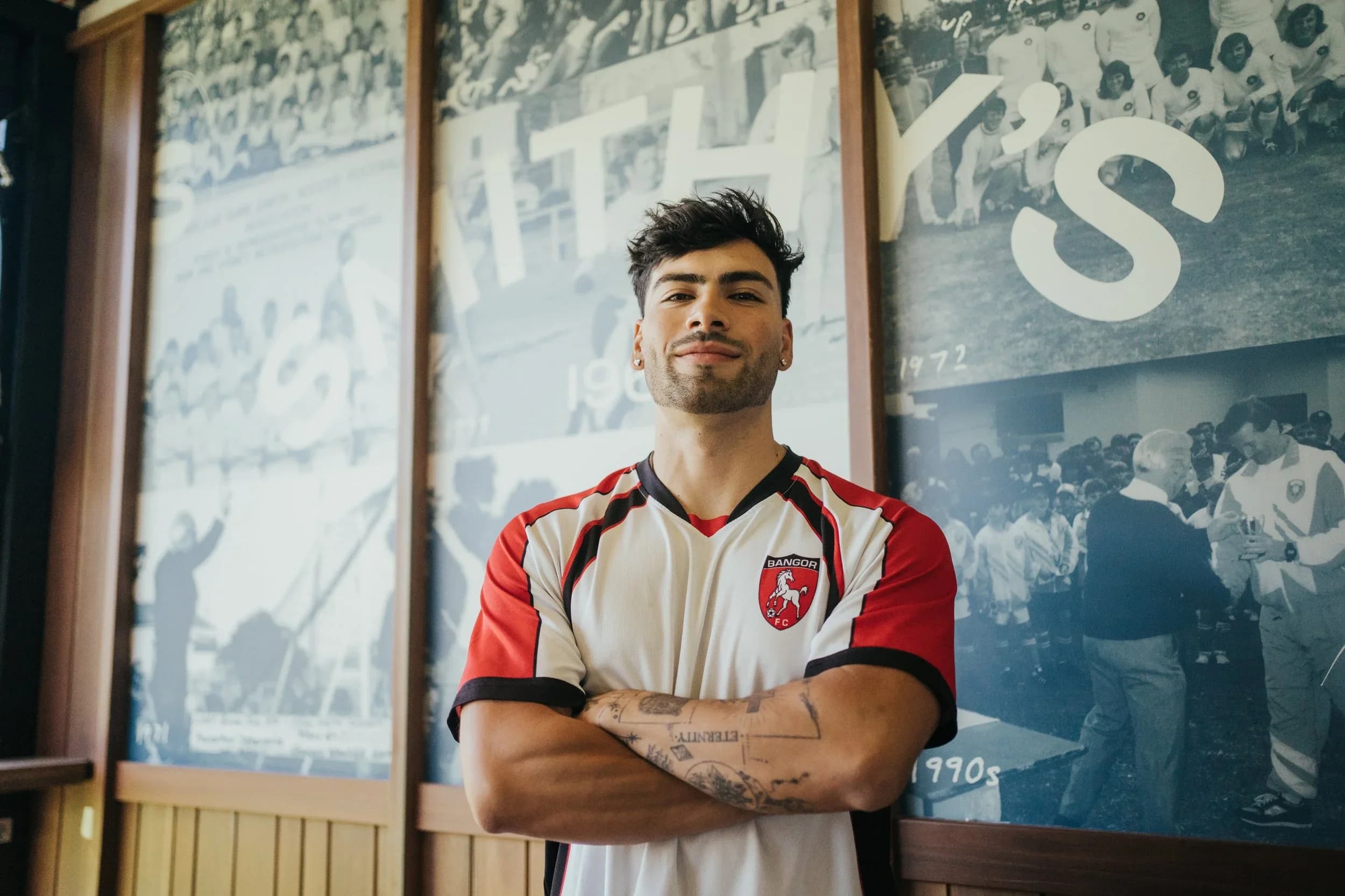 Jordan Perez, arms folded, in front of the club's historic photos