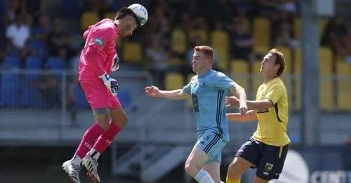 The Sharks goalkeeper in pink leaps for the ball as players challenge in the box