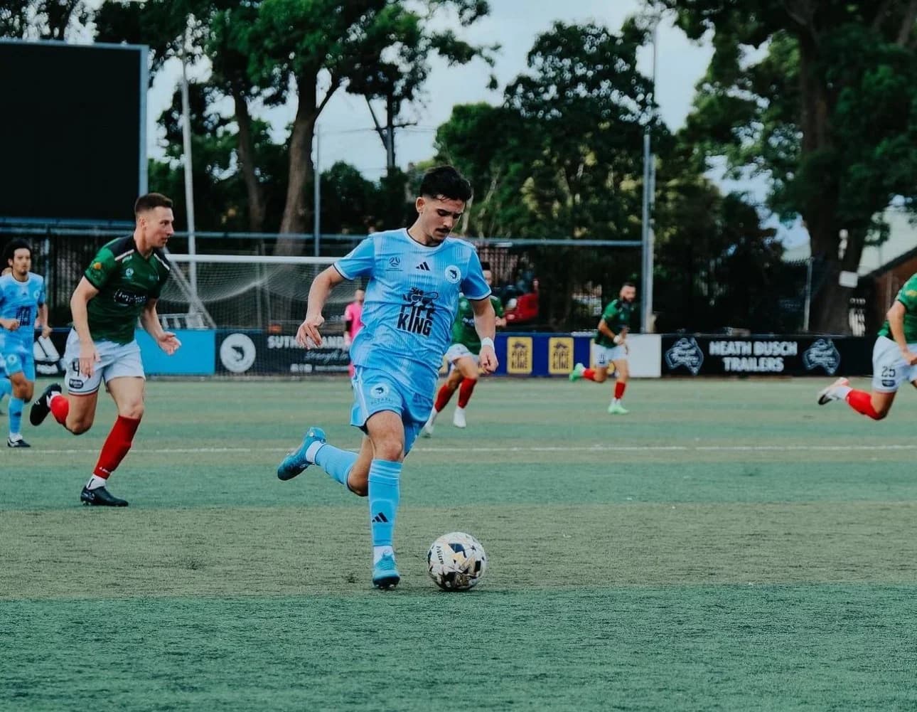 A Sharks player in sky blue runs with the ball against Marconi