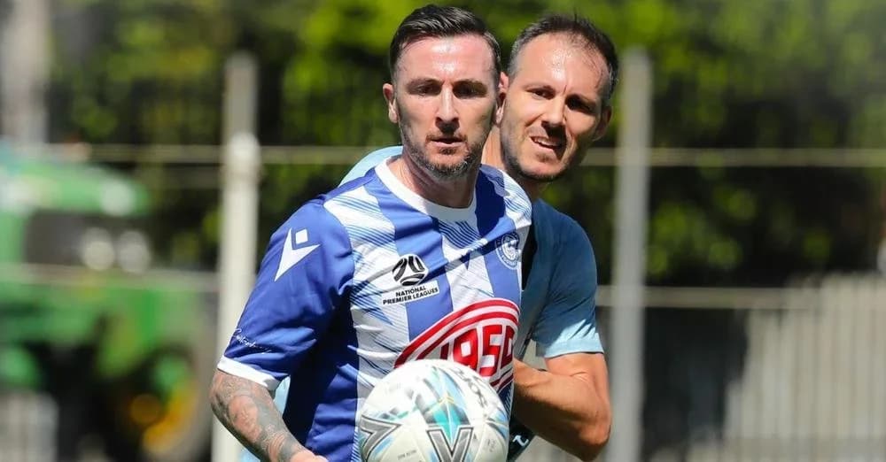 A Sydney Olympic player in blue and white holds the ball