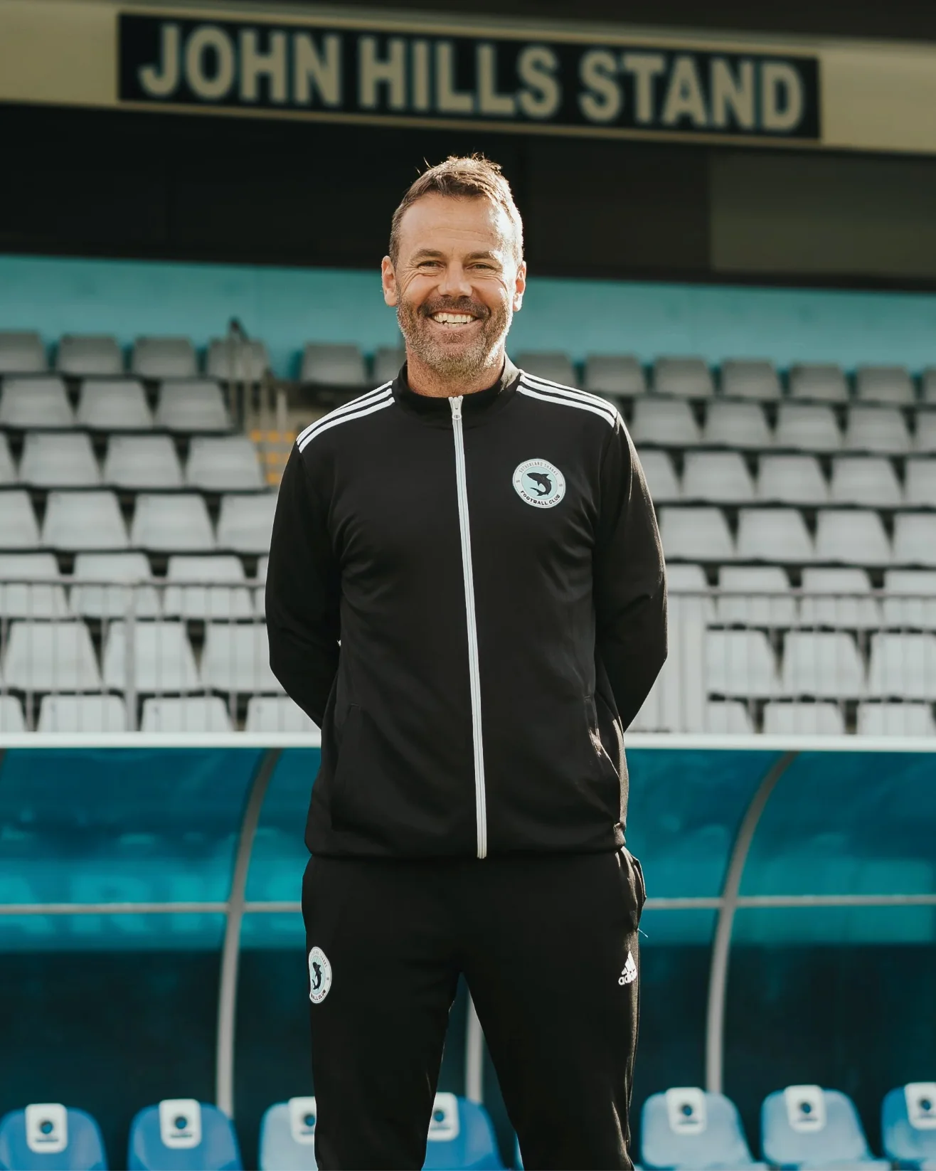 Paul Reid in a black club jacket in front of the John Hills Stand