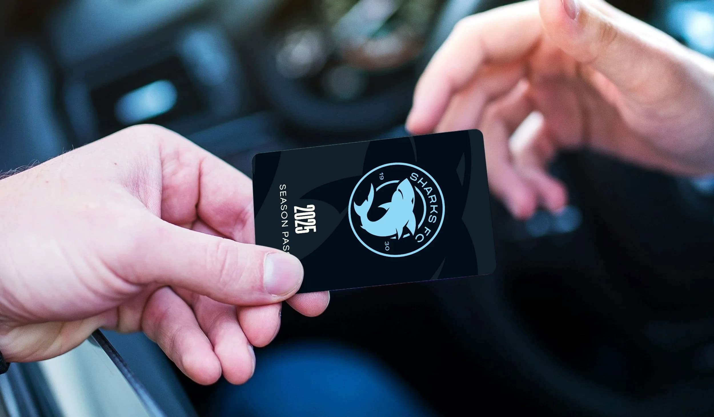 A hand holds a black Sharks season pass card