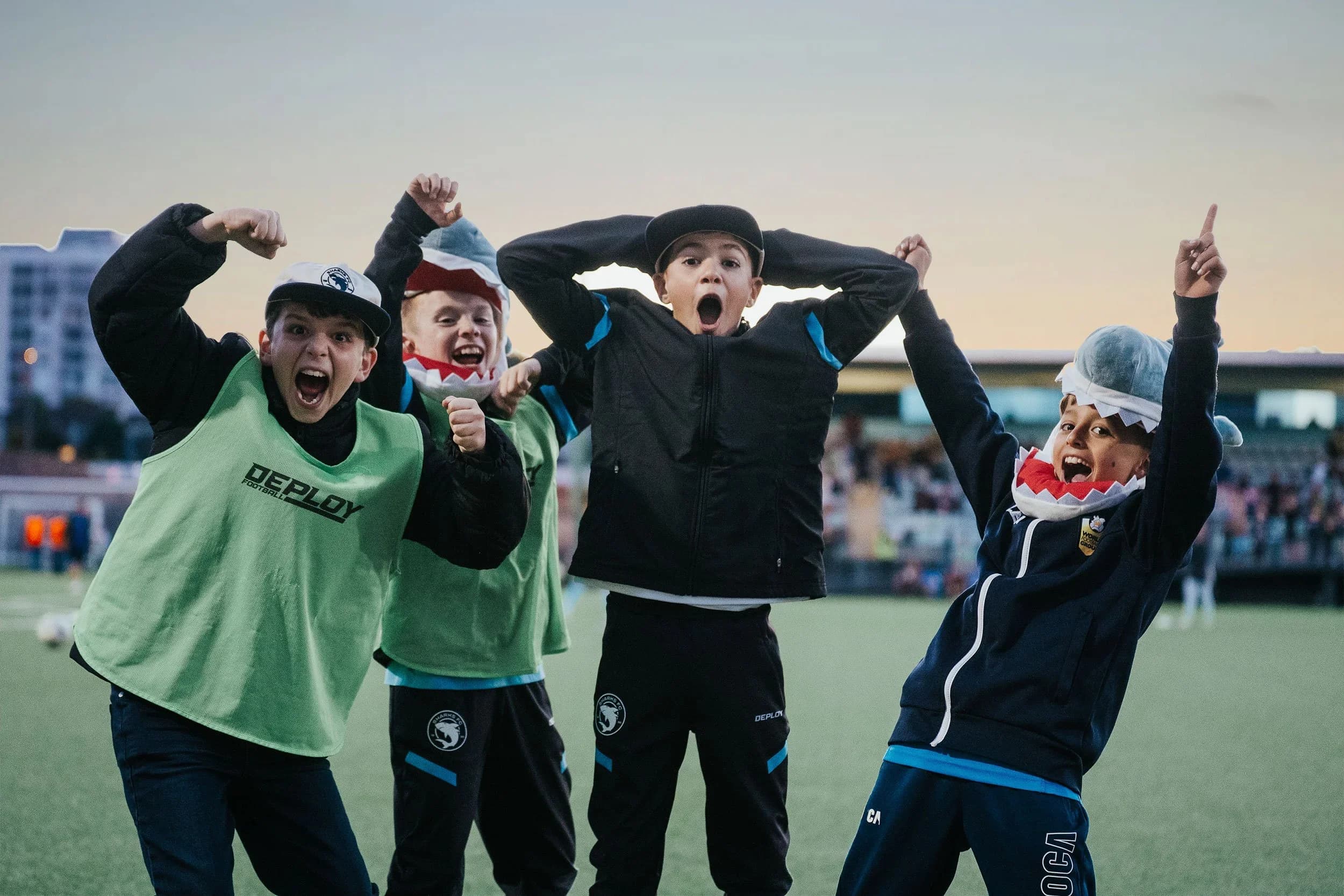 Young fans in Sharks gear cheer and point to the sky at family day