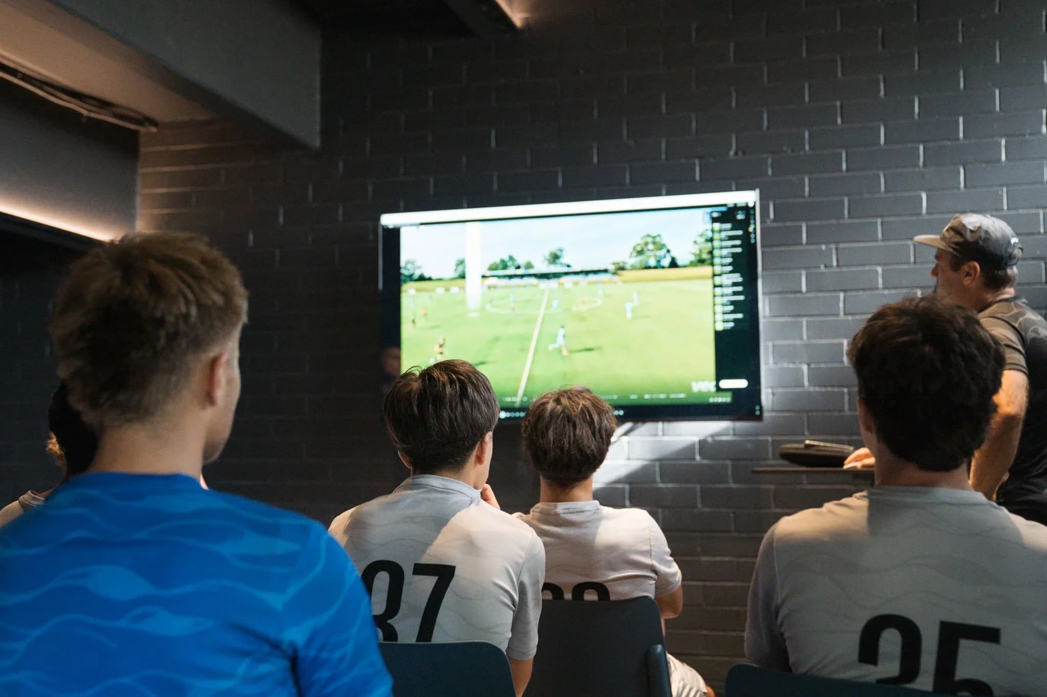 Young players watch match footage on a screen in the video analysis room