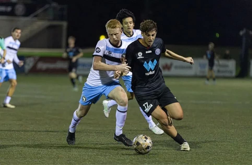 A Sharks player in black chases an opponent in white at night