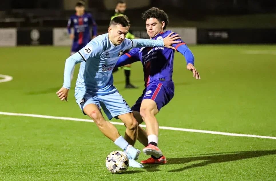 Danijel Nizic in sky blue shields the ball from an opponent in purple