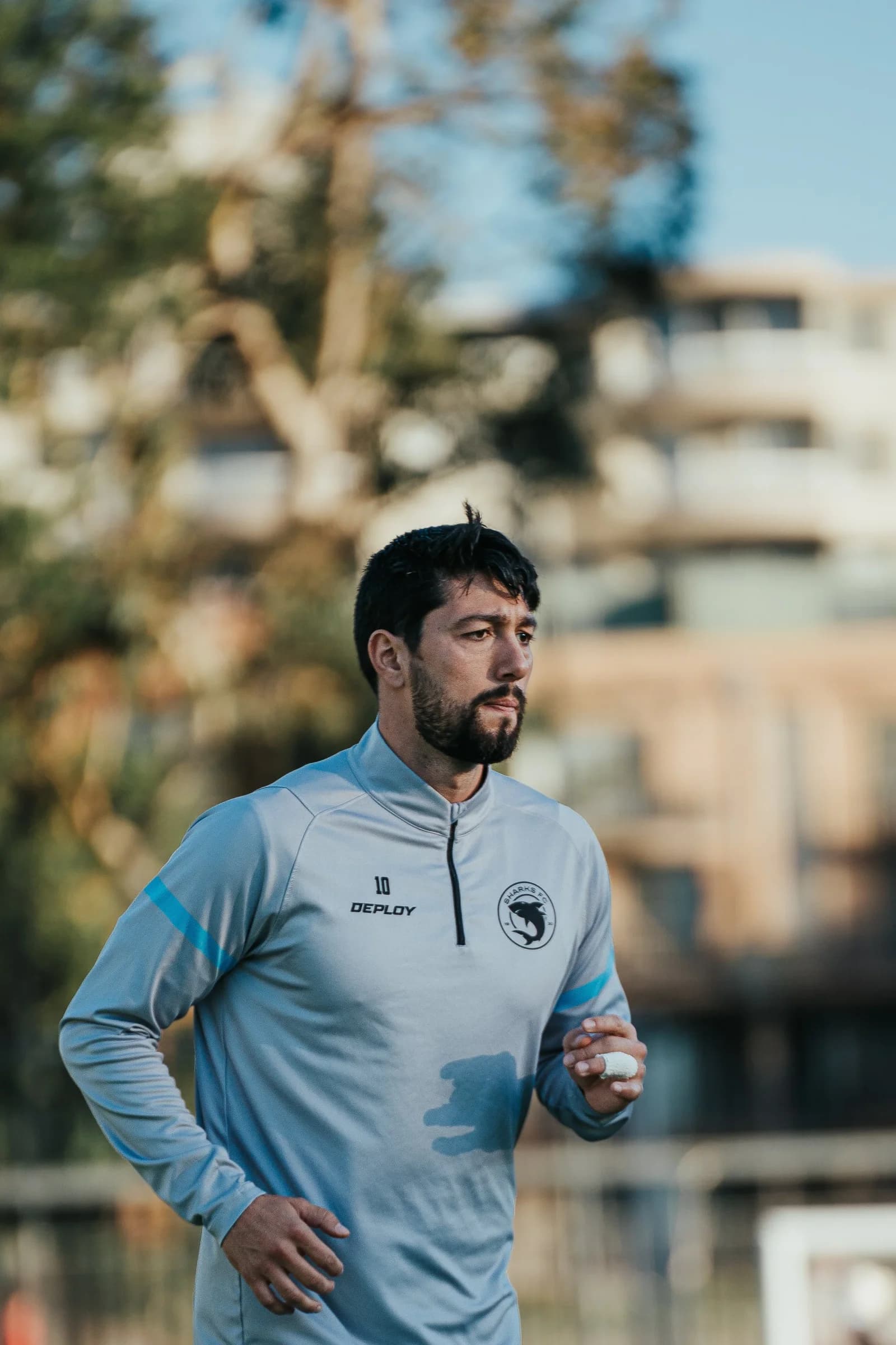 A Sharks player in a grey training top warms up