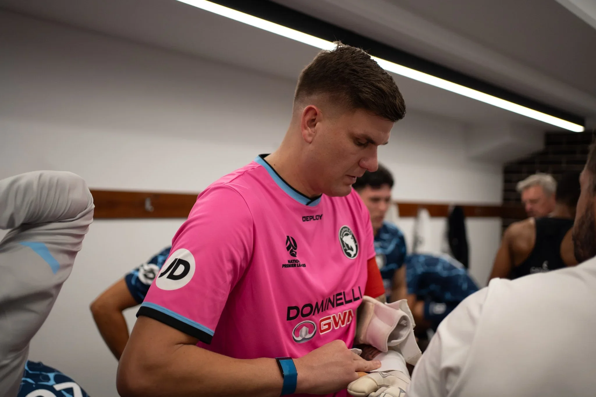A Sharks player in pink gets ready in the dressing room