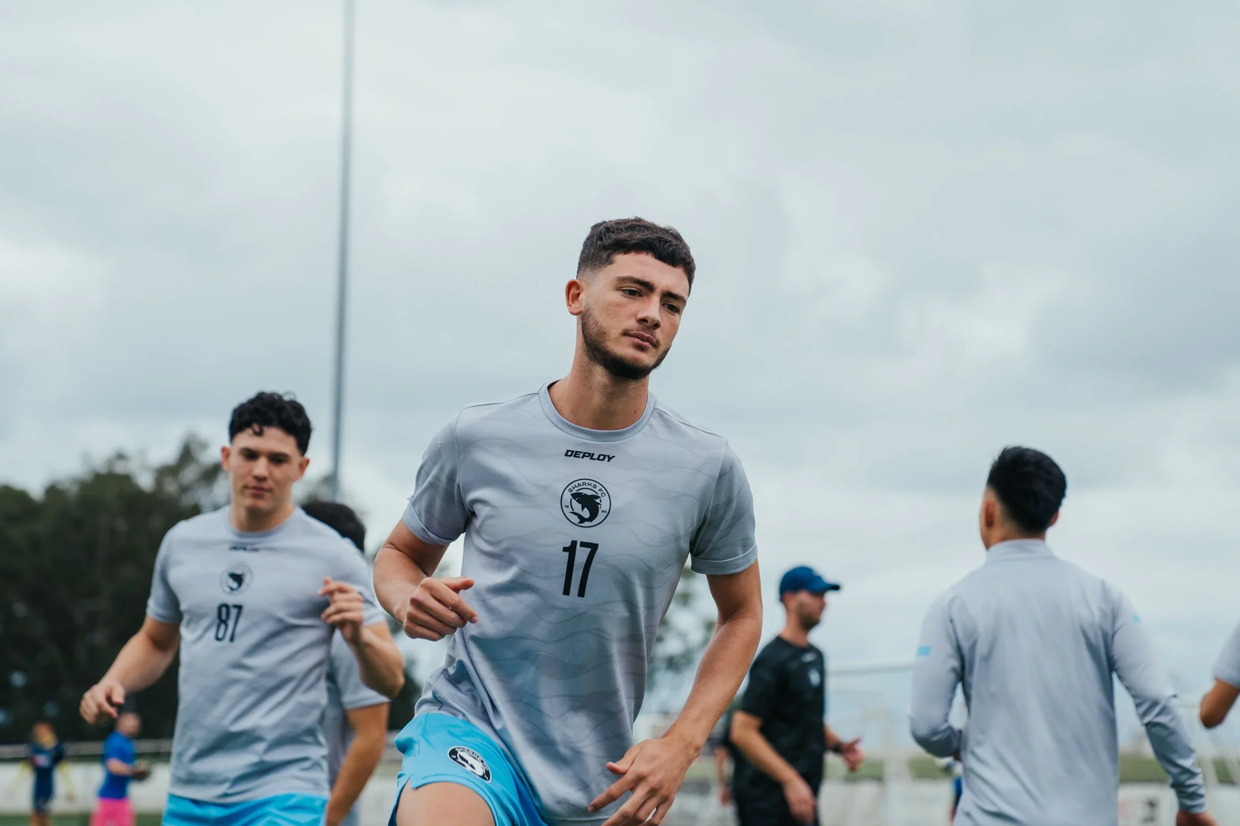 Shoueiki, number 11, and teammates jog in grey training tops before the match