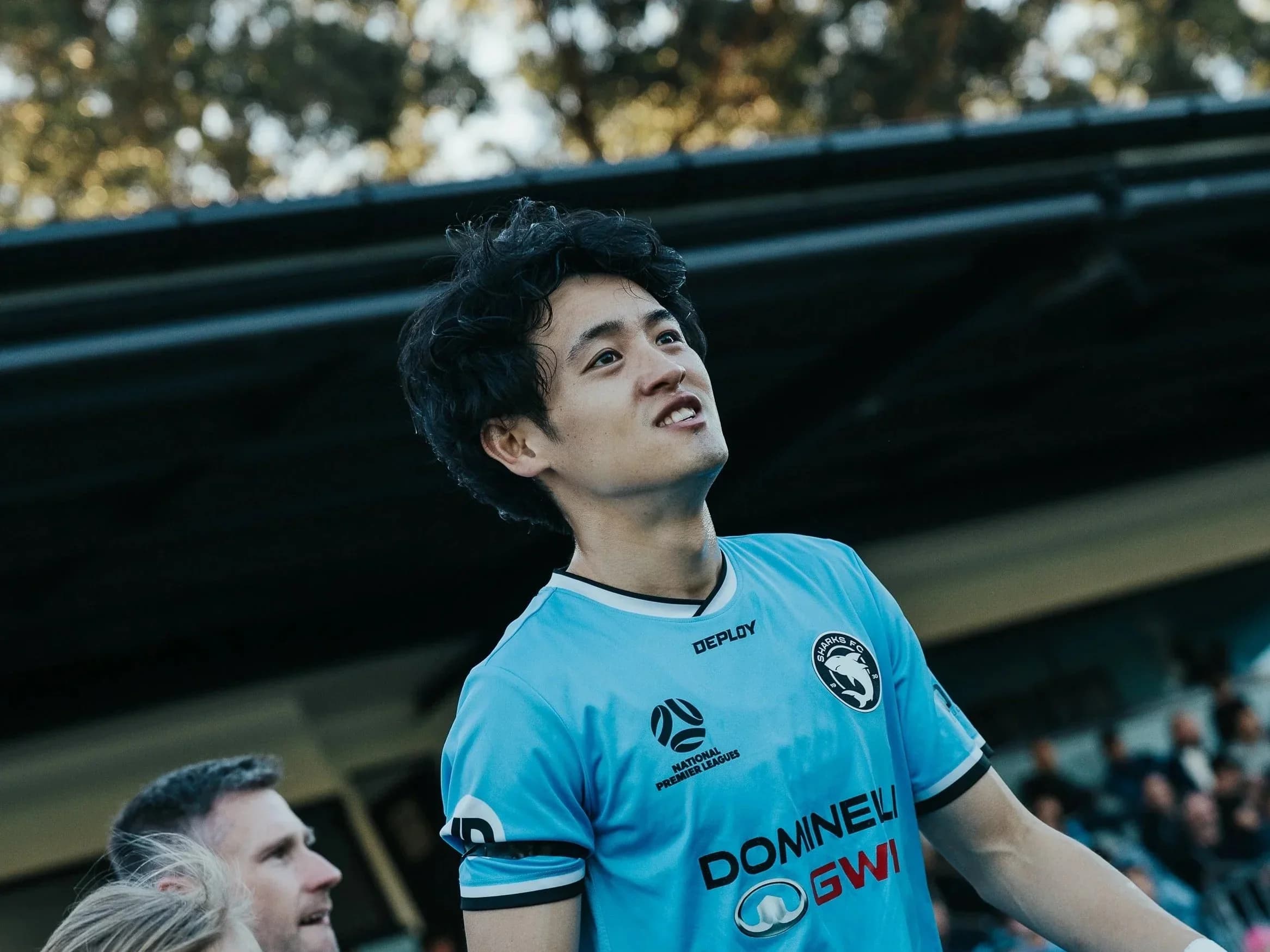 Kotaru in a sky-blue Sharks shirt looks up at the crowd