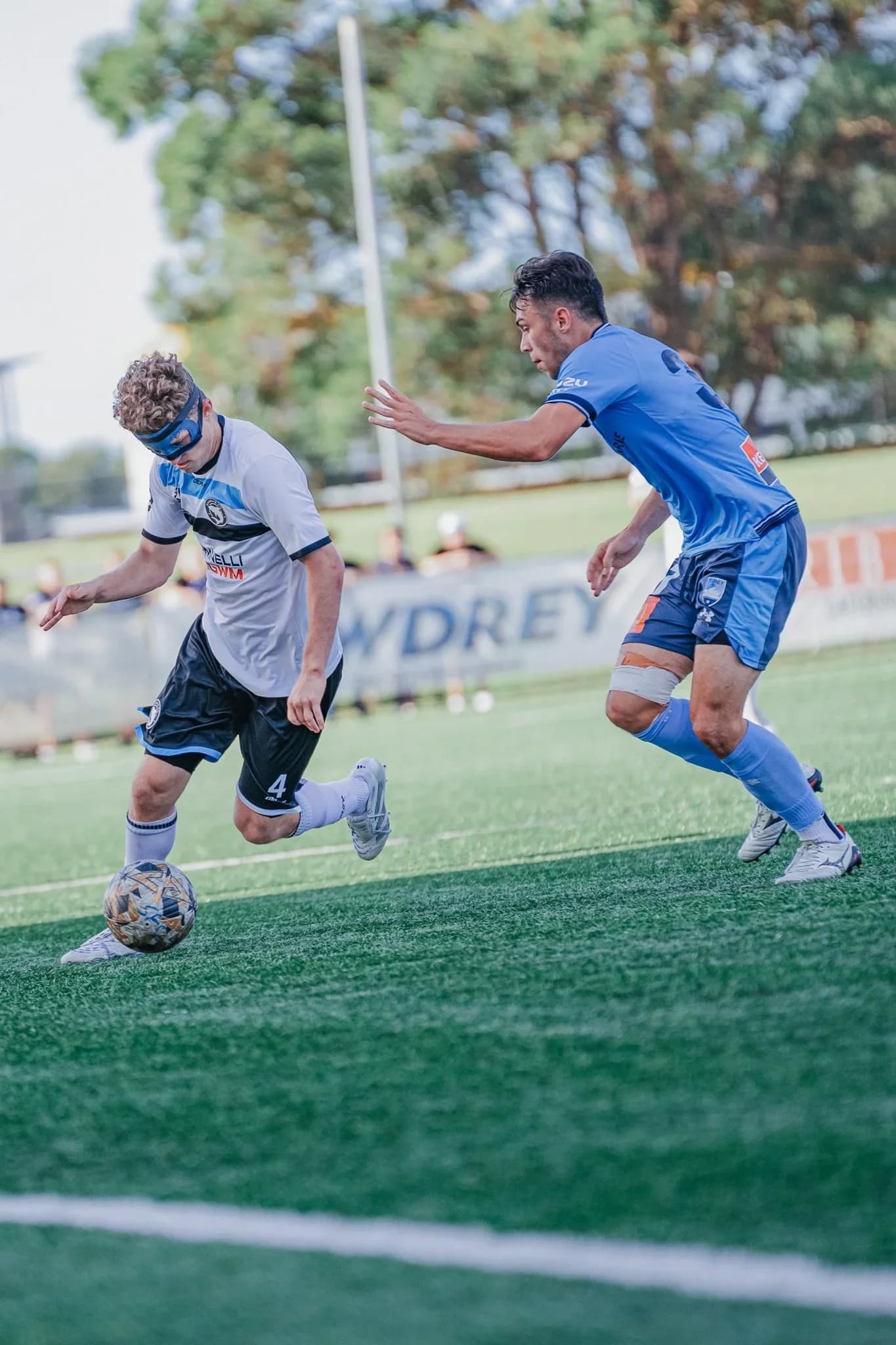 A Sharks player in white runs with the ball against an opponent in blue