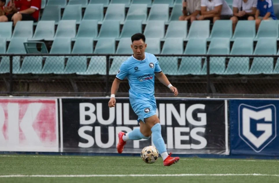 A Sharks player in sky blue runs with the ball in front of the advertising boards