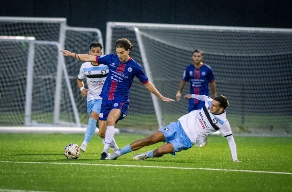 A Sharks player in white slides in to tackle a Manly player in blue