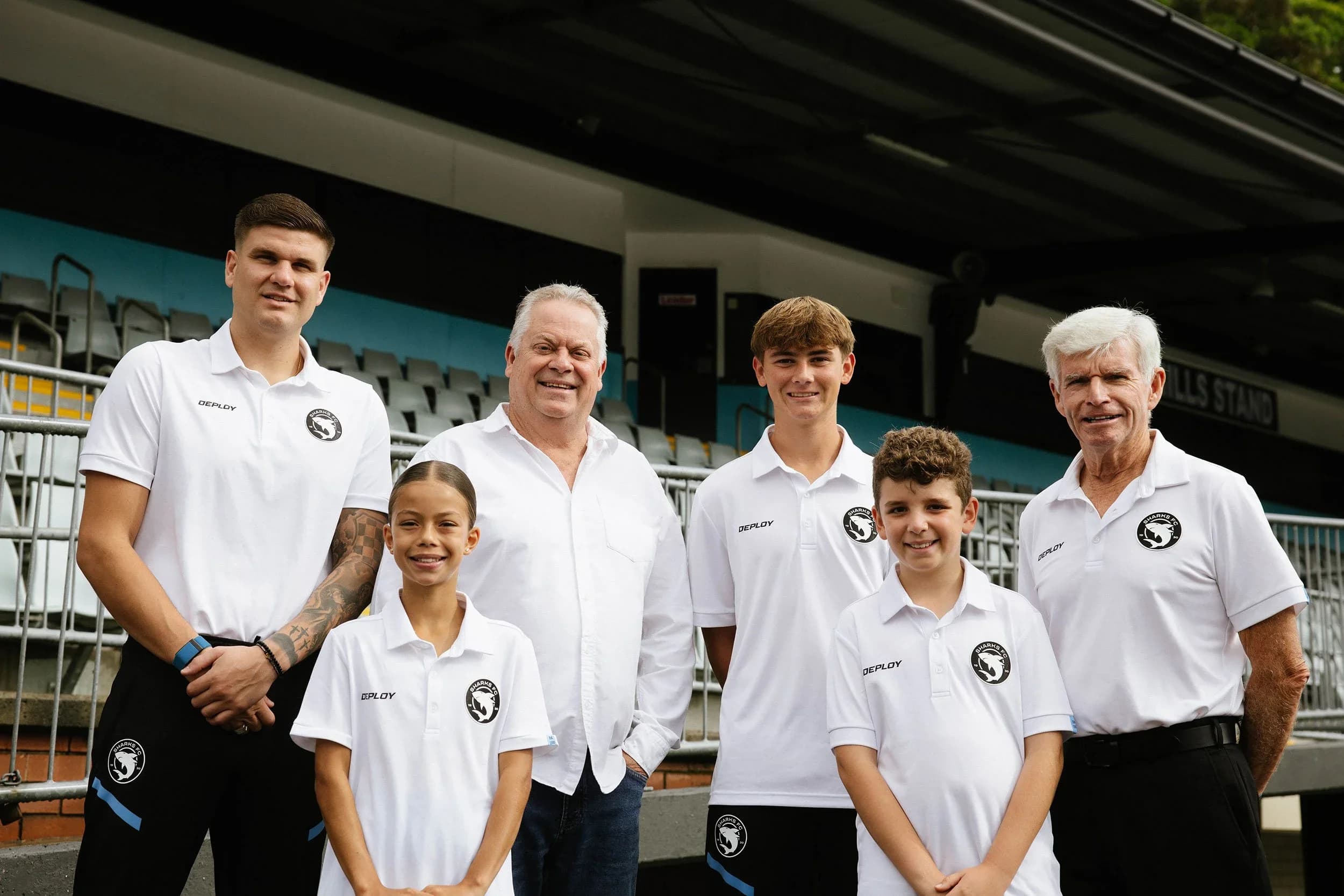 Greg O'Rourke with club officials and young players in Sharks polos in the grandstand