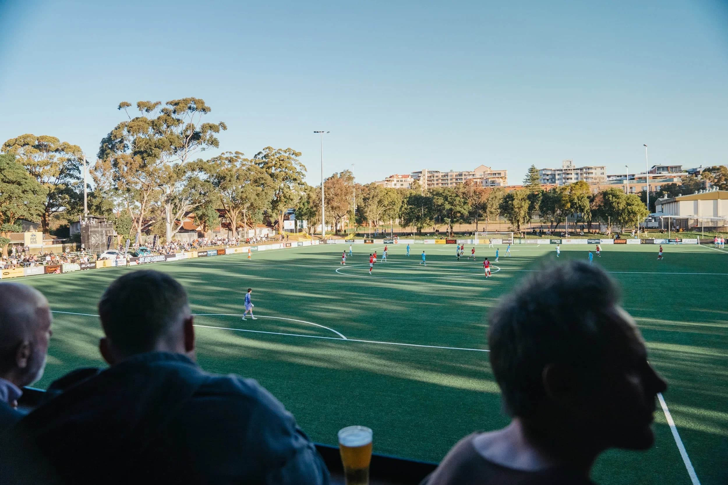 Spectators watching a match at Seymour Shaw from the stand on a sunny afternoon