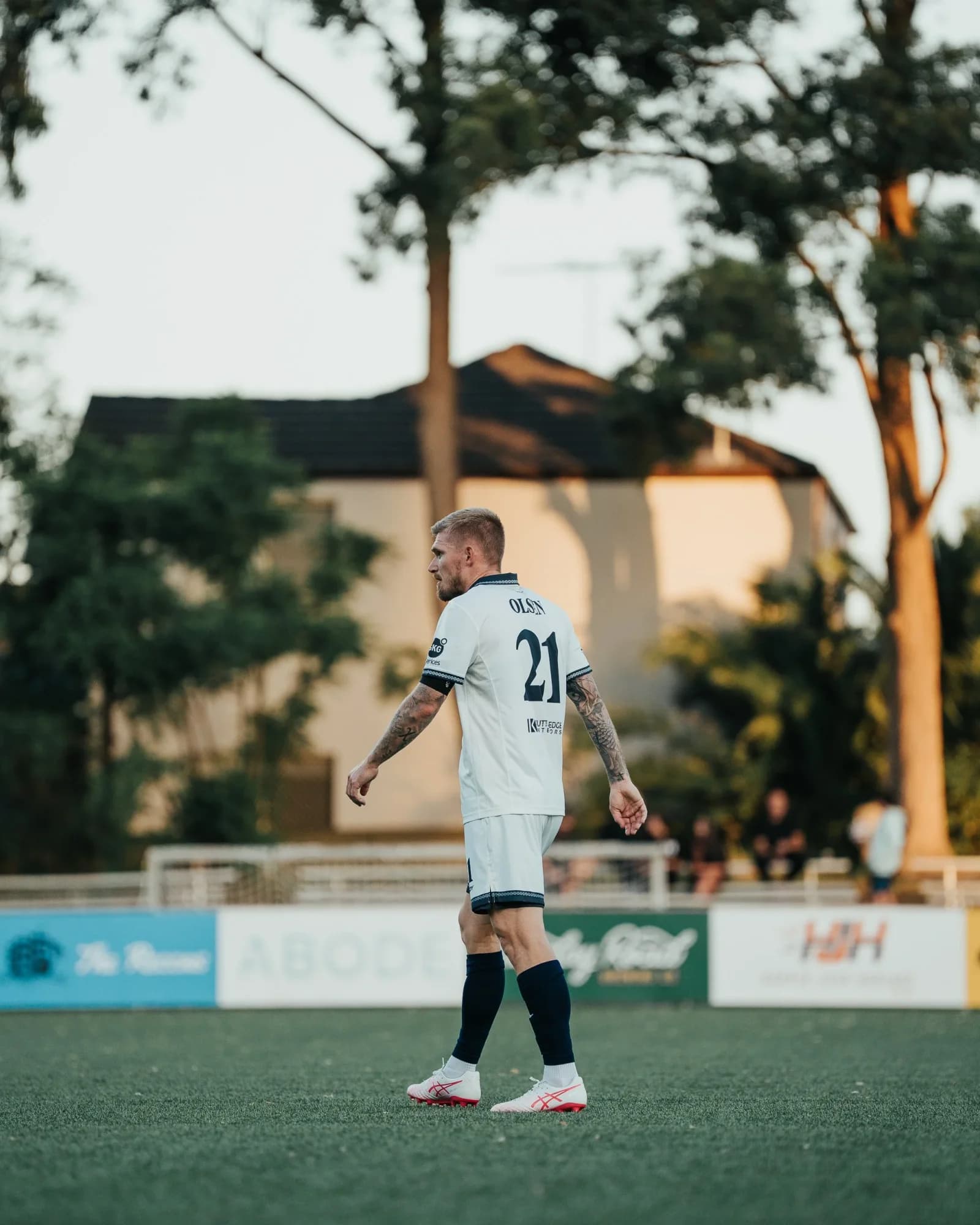 A Sharks player in white walks on the pitch beside gum trees