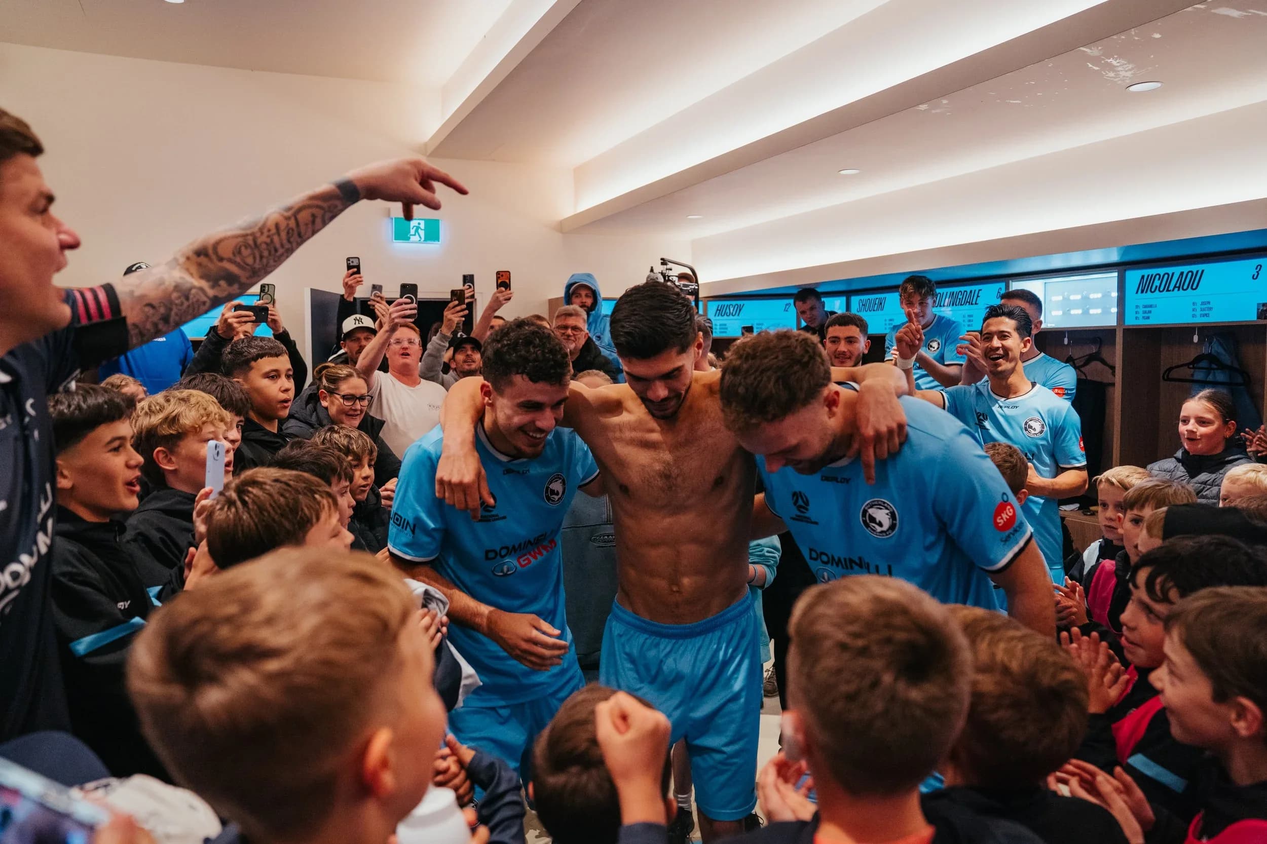Sharks players celebrate with young fans in the clubhouse after beating APIA