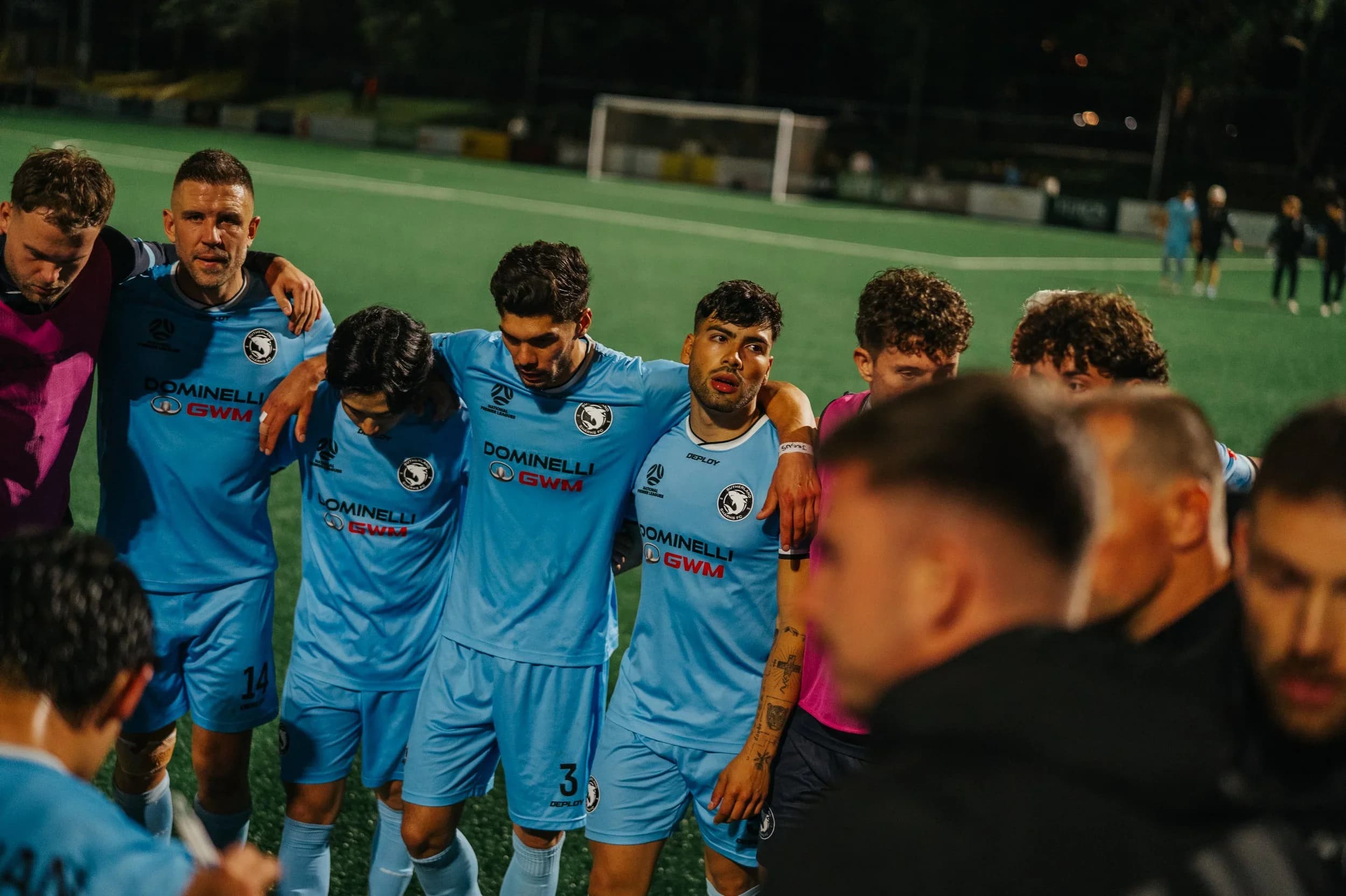Sharks players in a huddle on the pitch at night