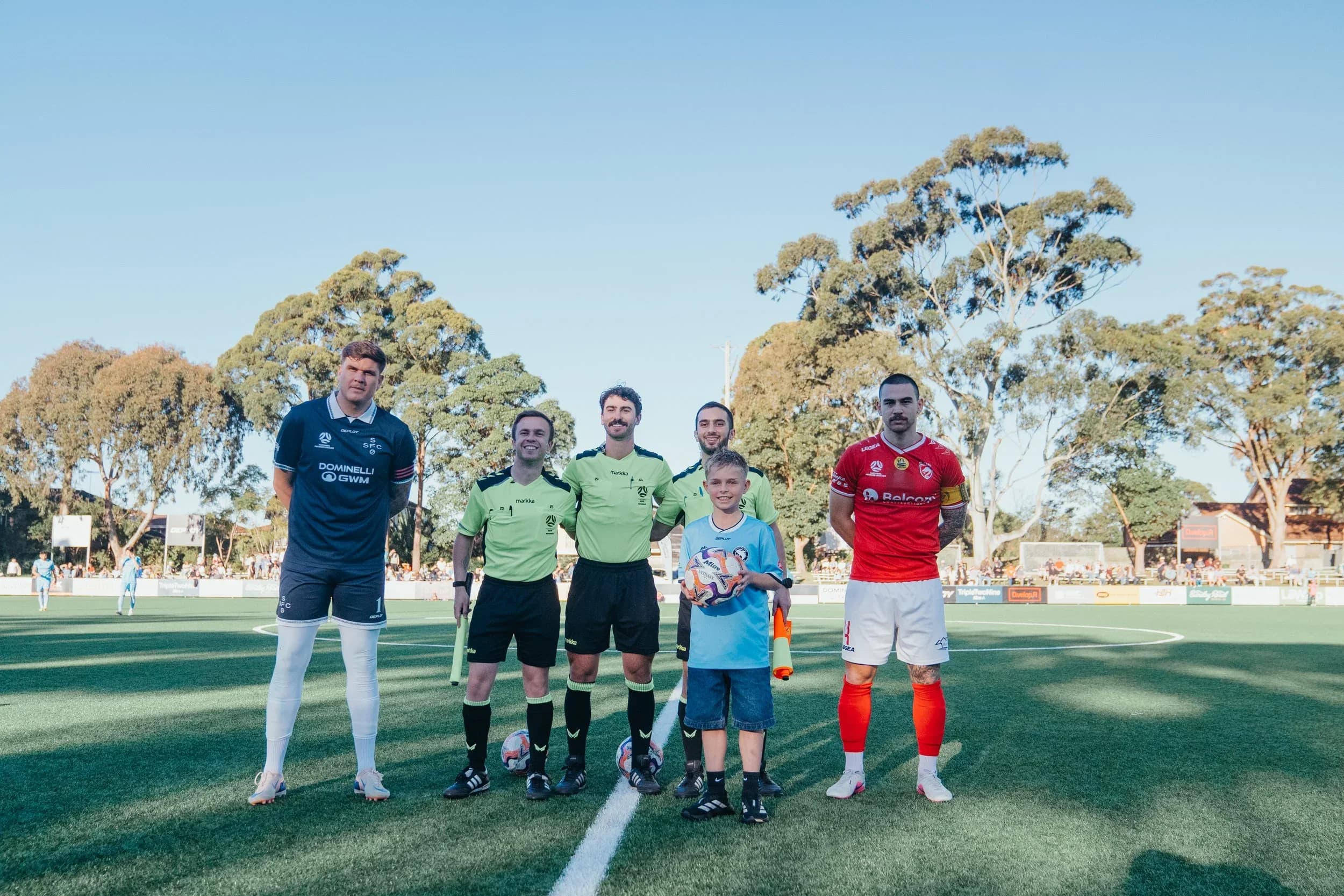 The two captains, a young mascot and the referees line up for the coin toss before the match