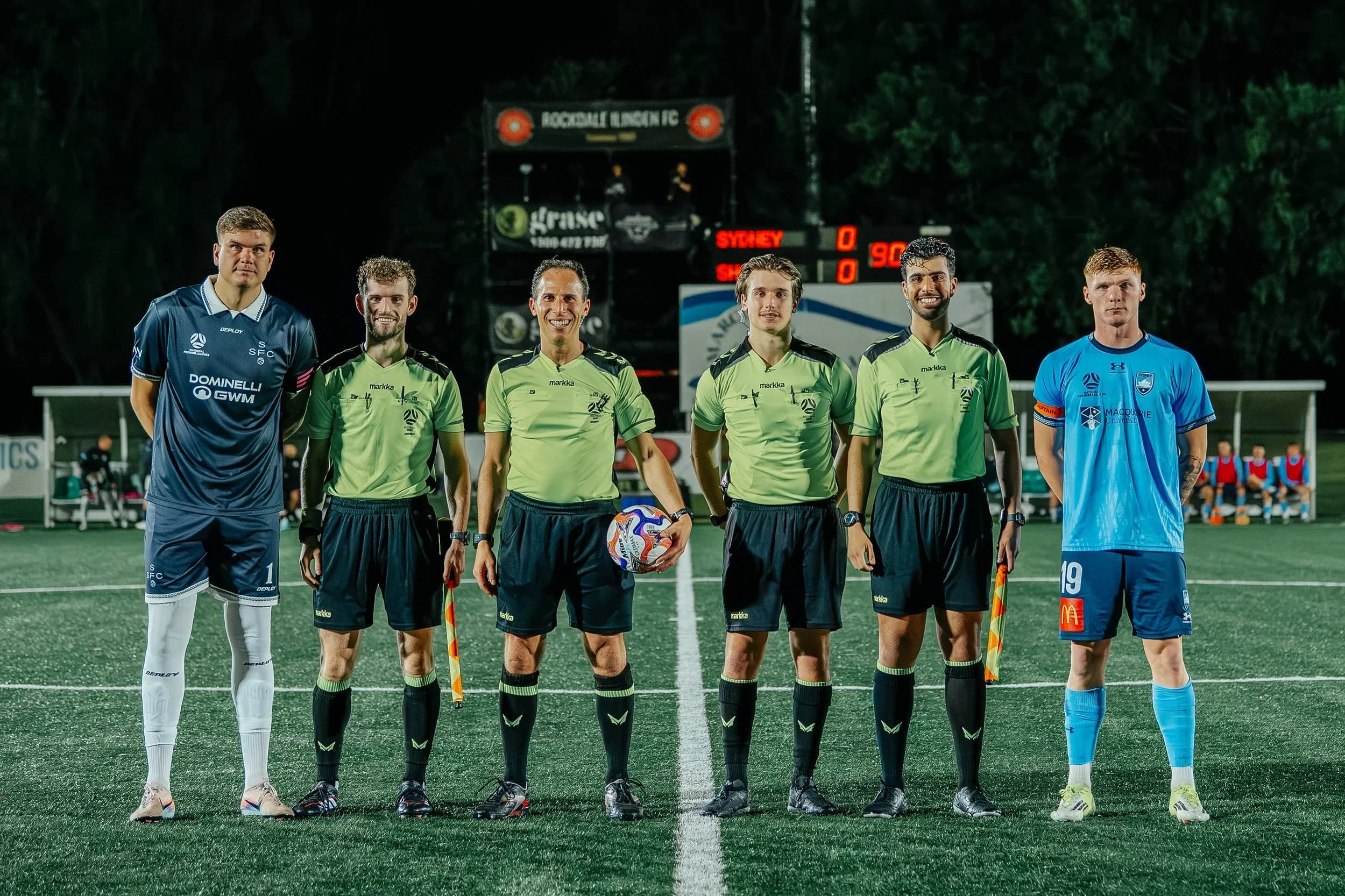 The two captains and the referees line up before the match against Sydney FC