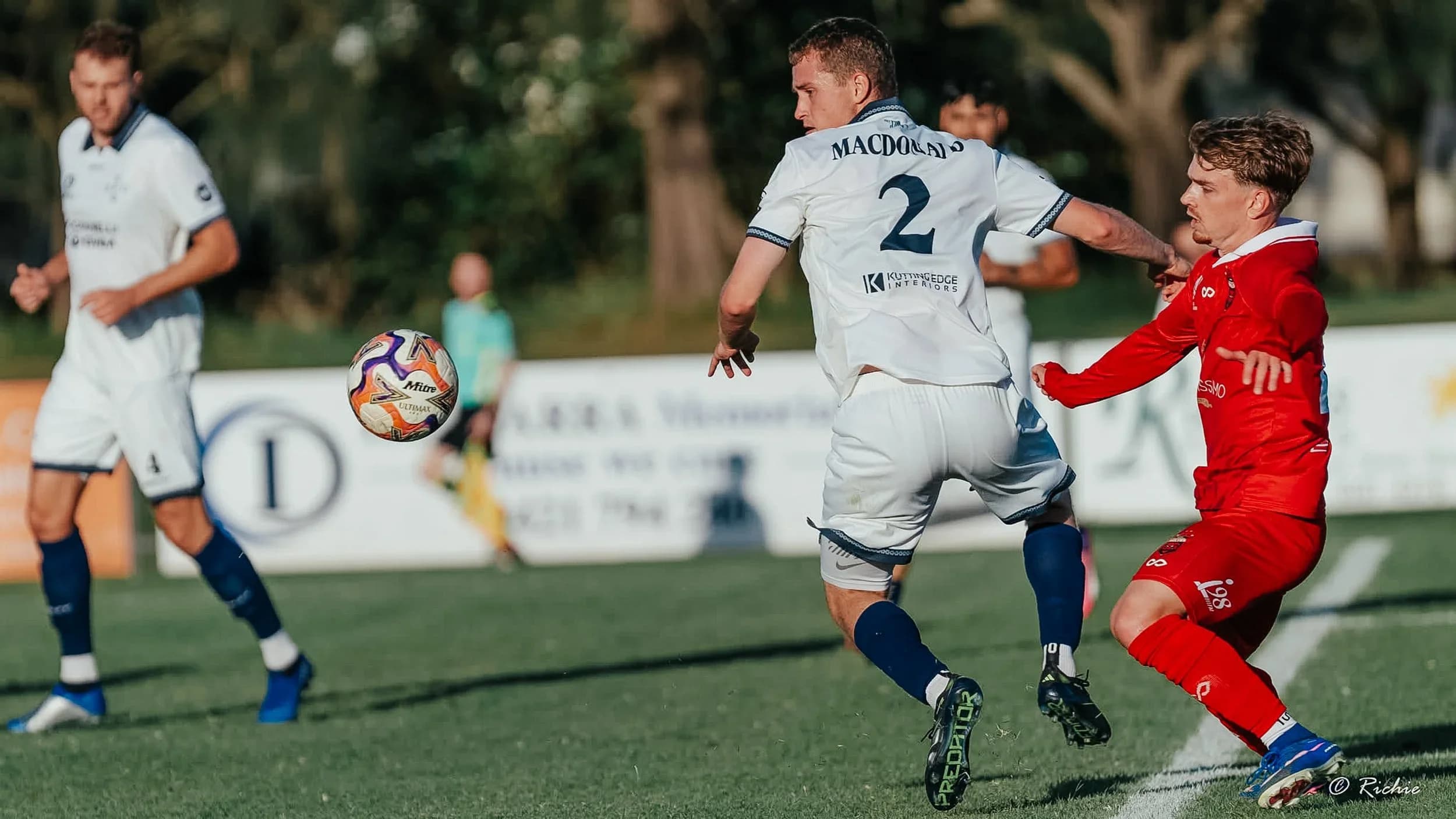 A Sharks player in white, number 2, holds off a Wolves player in red