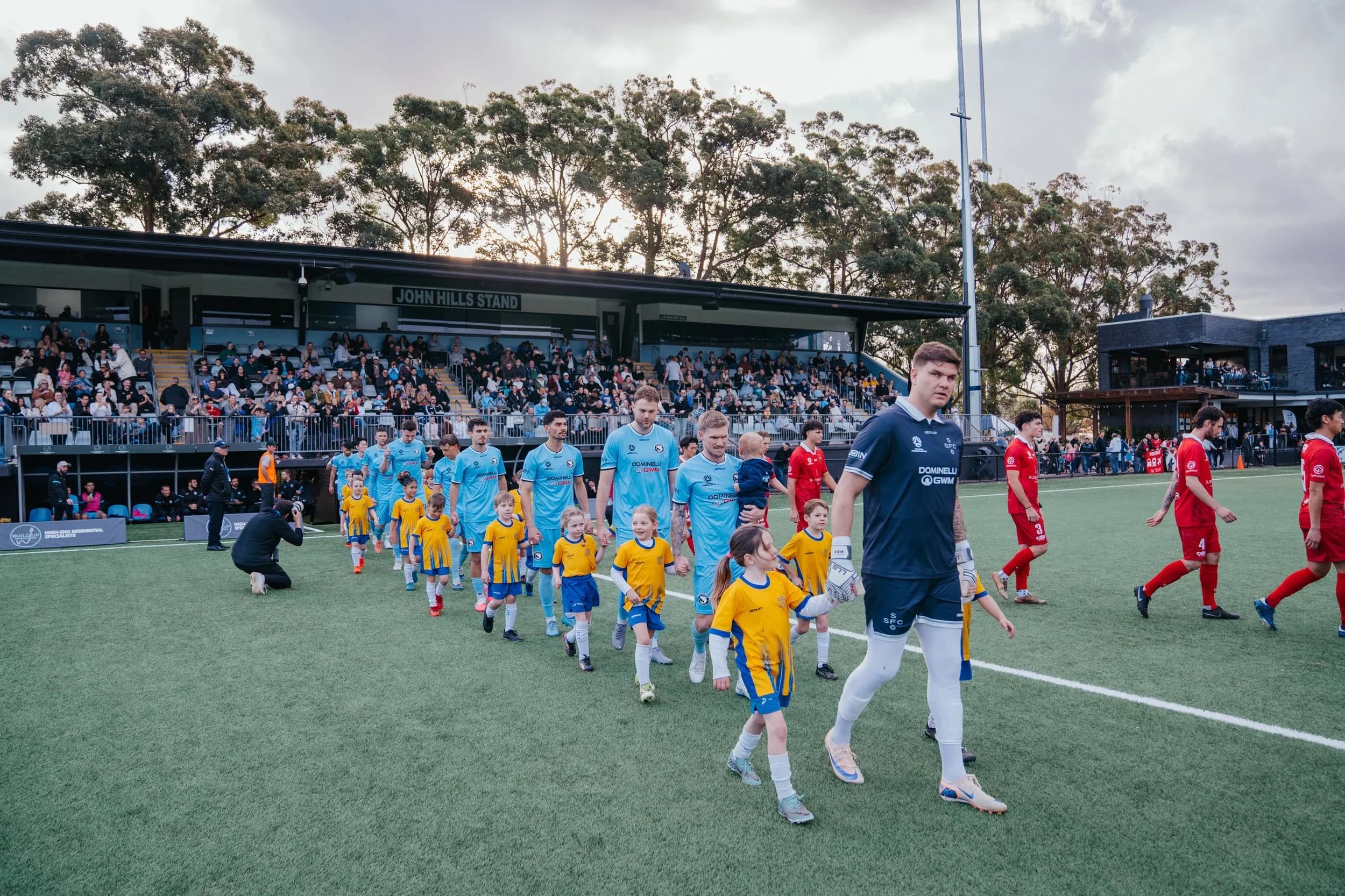 The Sharks and Wollongong Wolves walk out with junior mascots in front of a full stand