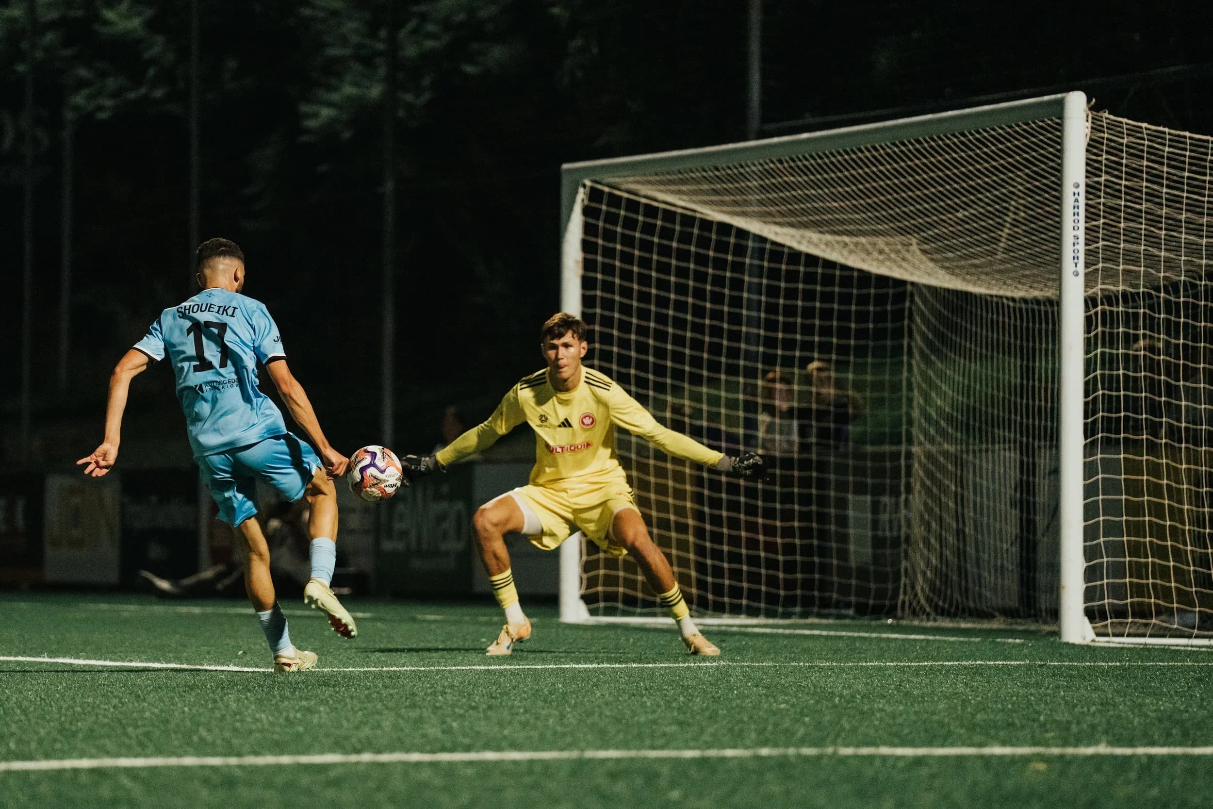 A Sharks player shoots past the Wanderers goalkeeper in yellow