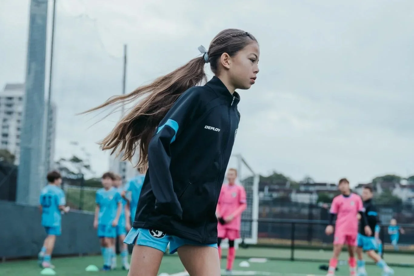 A young Sharks girl in a navy training top runs during a session at Seymour Shaw