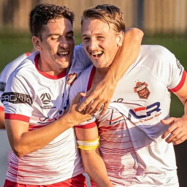 Two Wolves players in white embrace after scoring