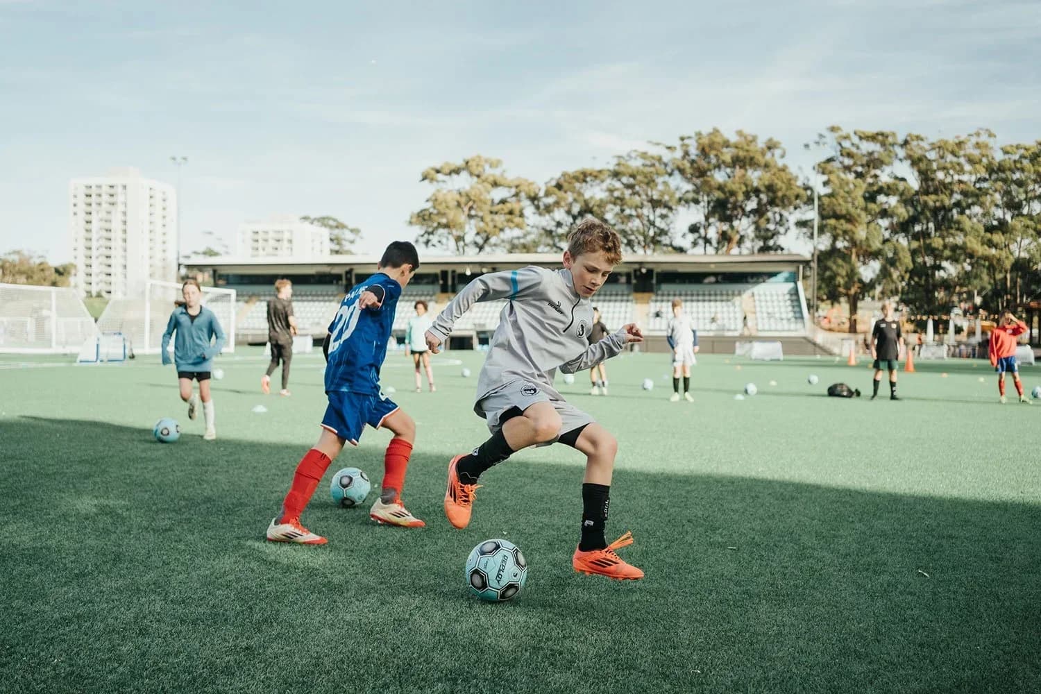 A young player in white dribbles at a clinic at Seymour Shaw